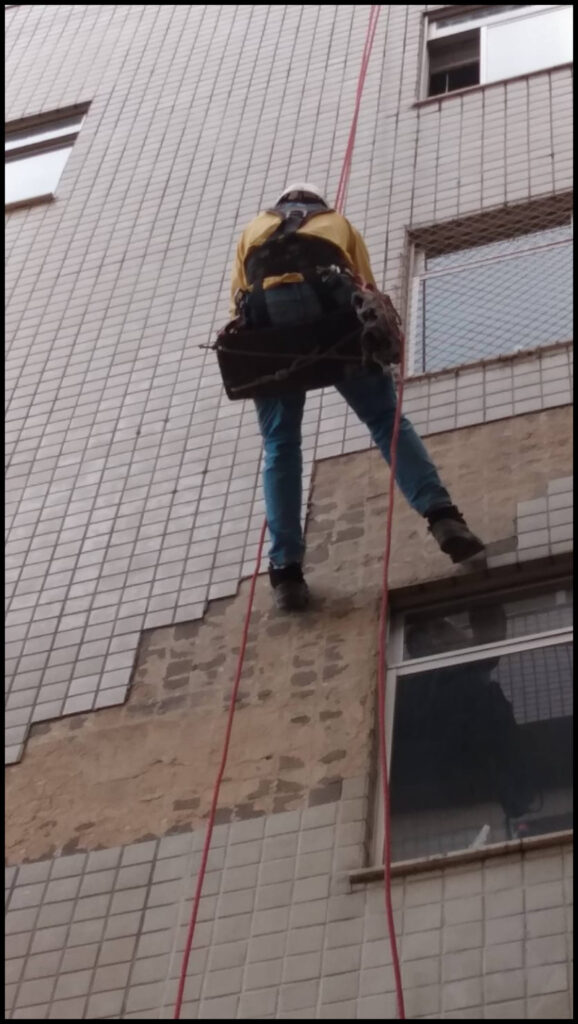 Profissional da Vertical Chão trabalhando na reposição de pastilhas em fachada