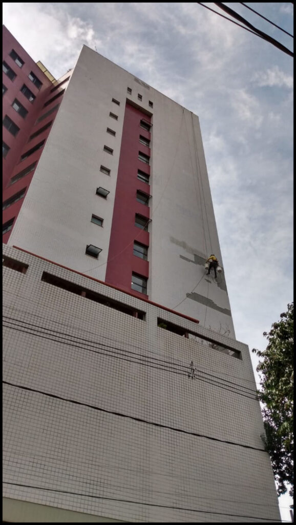 Profissional trabalhando em fachada alta de edifício
